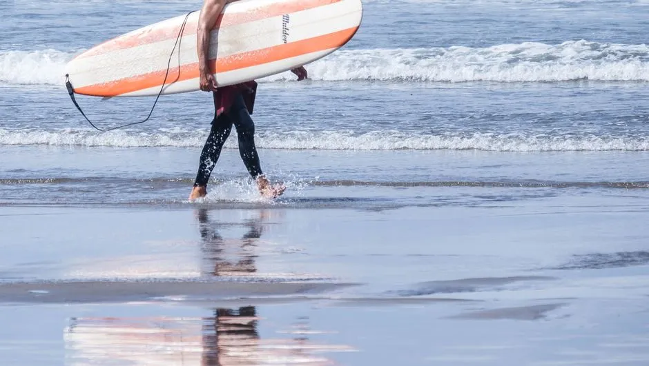 Carrying the board across the wet sand near Avilés